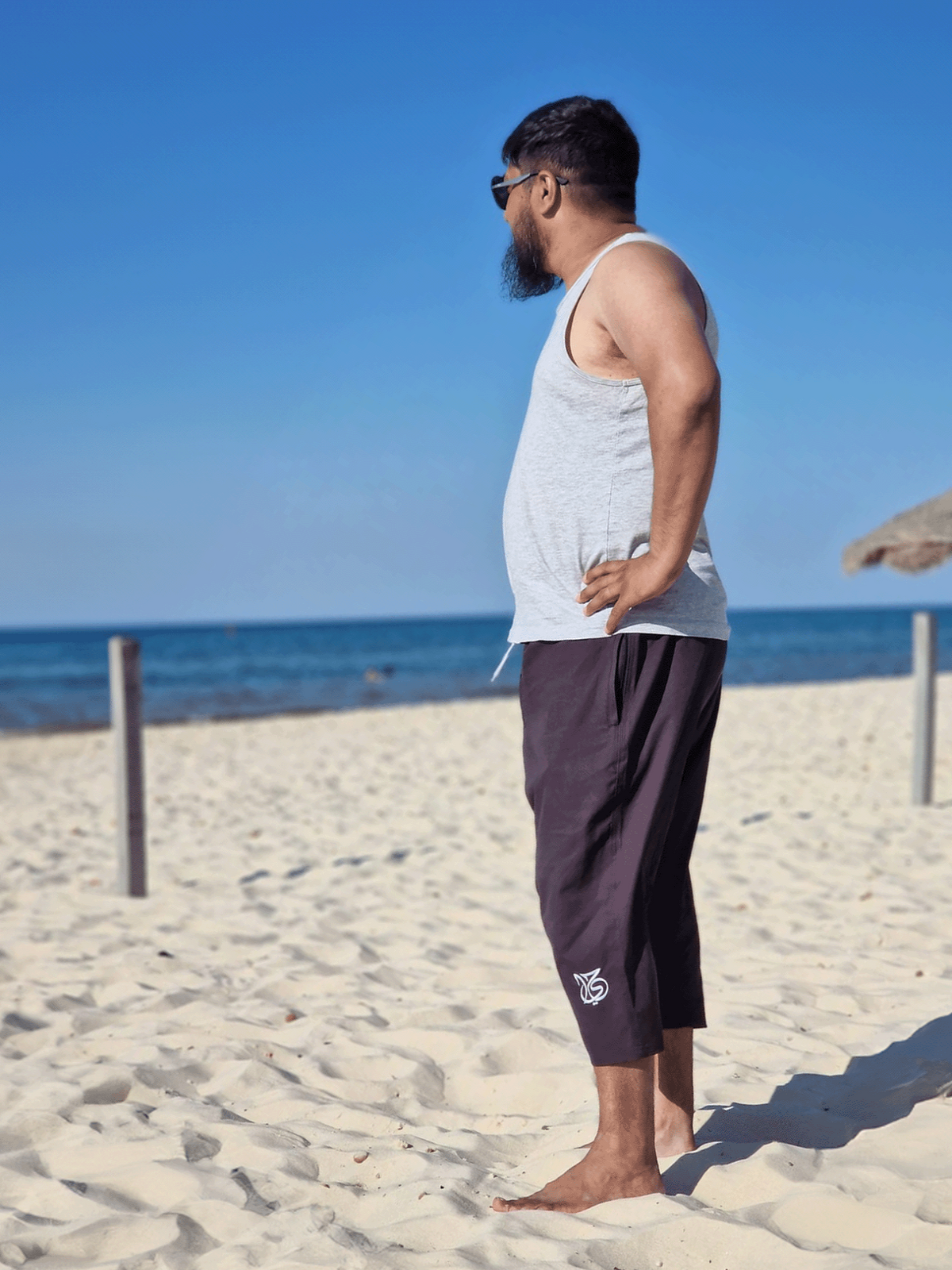 Man stood on beach wearing ZAYFA islamic Swim Shorts looking at ocean